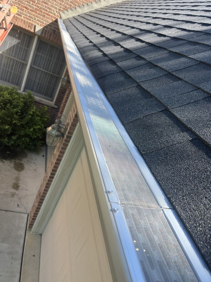 Micro-mesh gutter guard running the full length of a gutter above a garage on a brick home