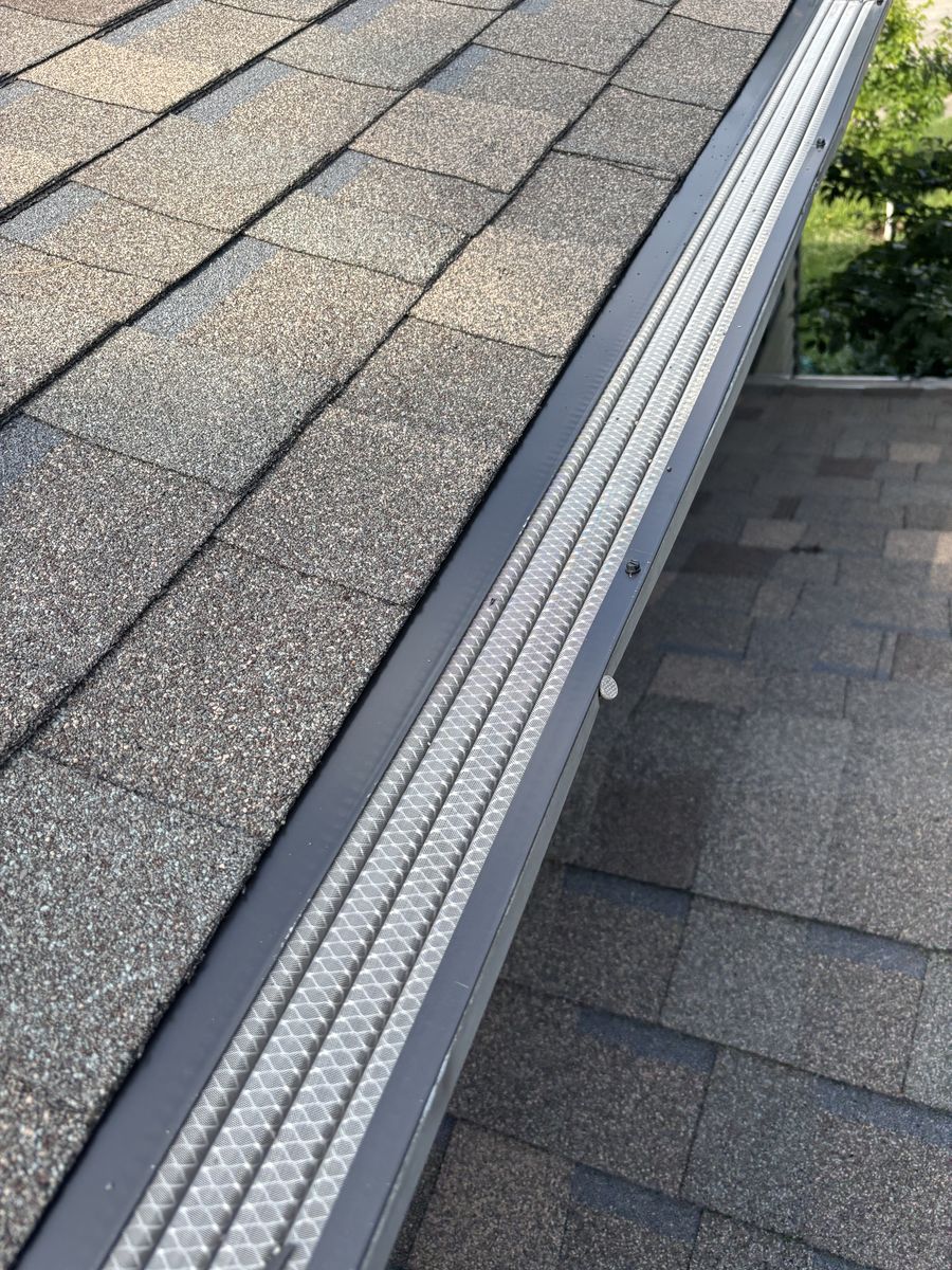 Close-up of stainless micro-mesh gutter guard installed along a shingled roof valley